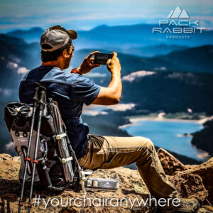 Hiker sitting in backpack seat overlooking valley