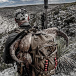 Hunter wearing tan backpack looking out at the desert landscape