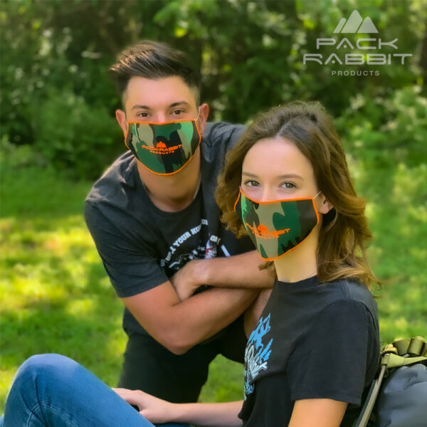 young couple wearing face masks in woods