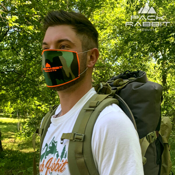 man wearing camo face mask and backpack in woods